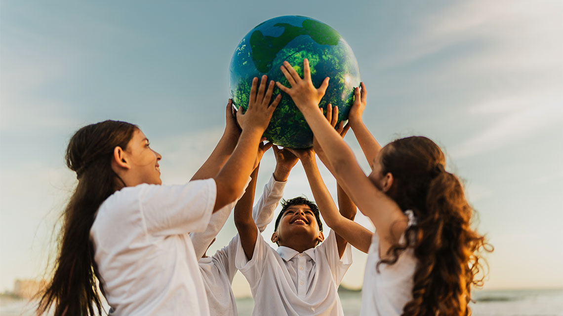 Three young people hold up a globe.