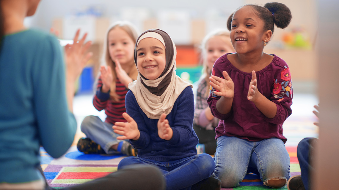 Students are smiling and following their teacher to clap together.