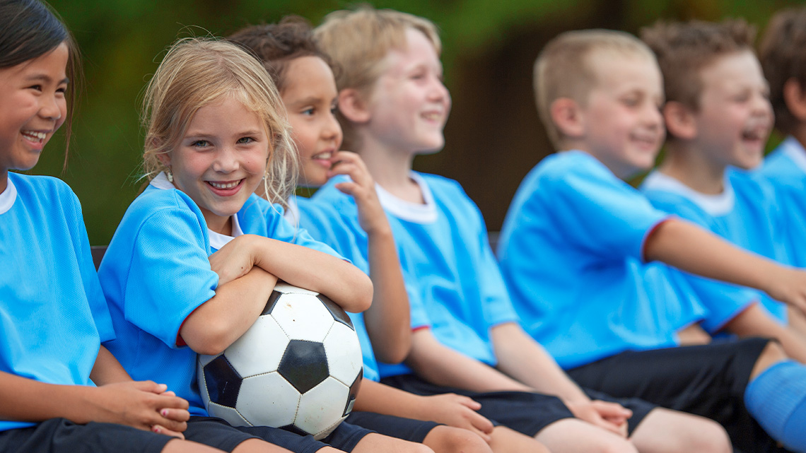 A group of children are learning to play soccer and are part of a soccer team.