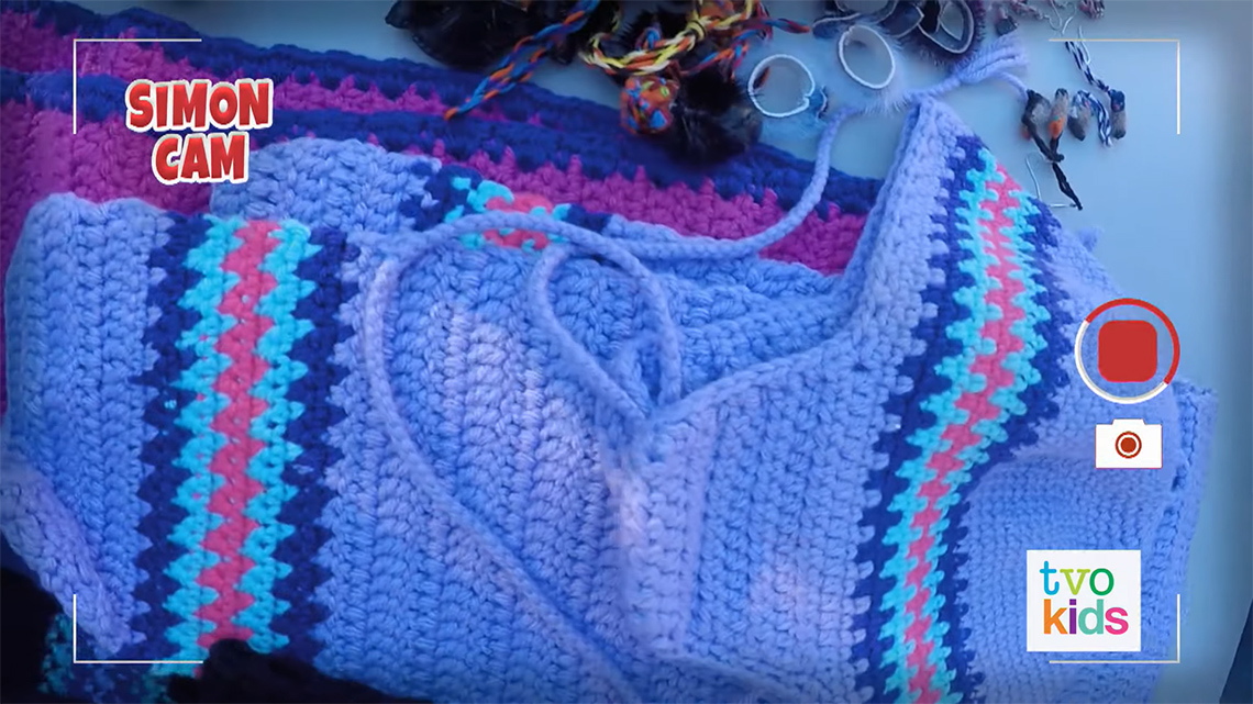 A table with several pieces of clothing that are knitted or crocheted.