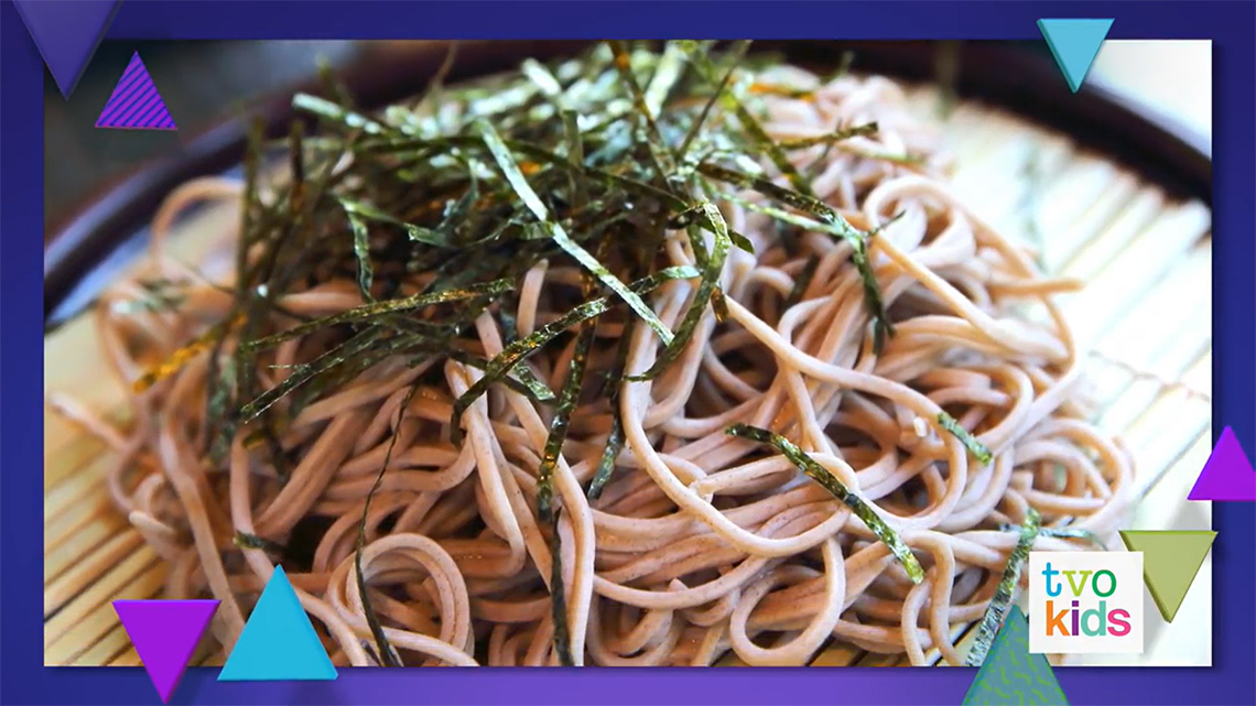A dish with many soba noodles, which are topped with thin strips of seaweed.