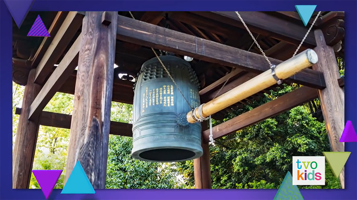 A large outdoor bell with a large mallet for people to use to ring the bell.