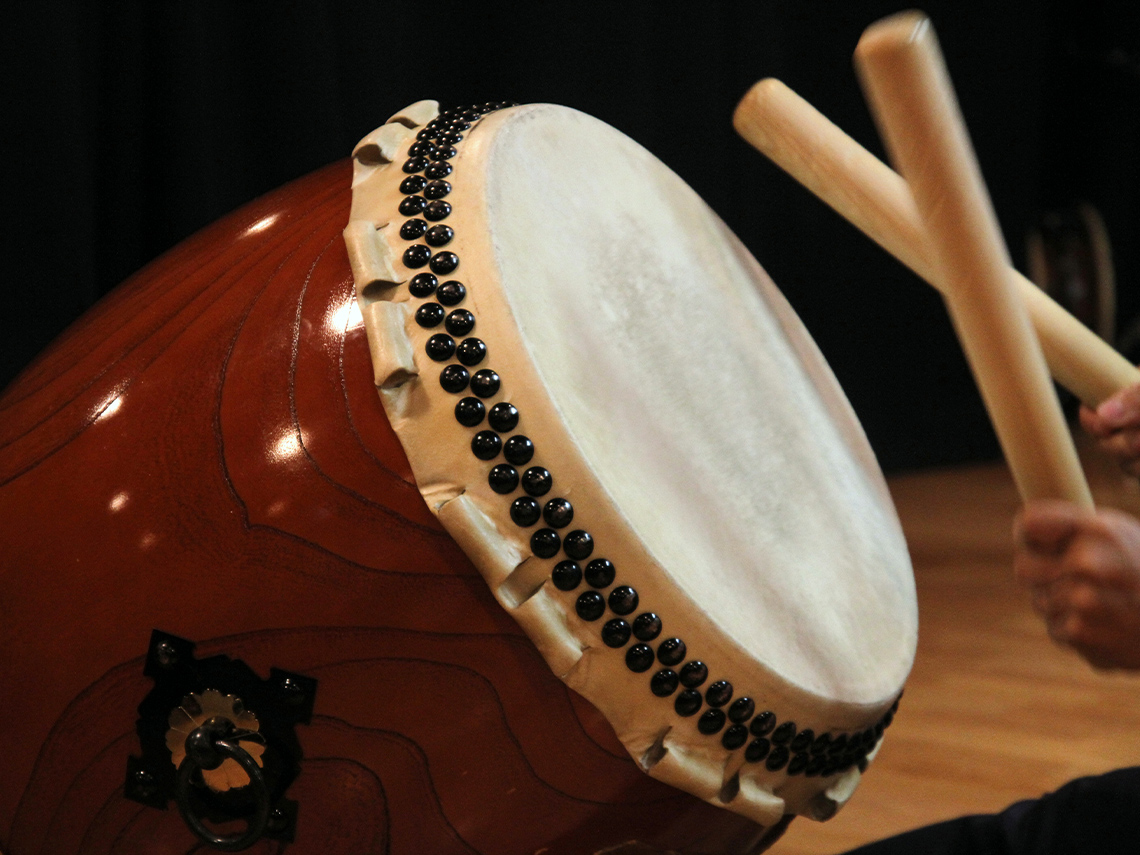 A large taiko drum being played with two special wooden drum sticks called bachi.