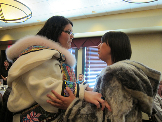 Two Inuit throat singers facing each other. One of the singers is holding a microphone between them.
