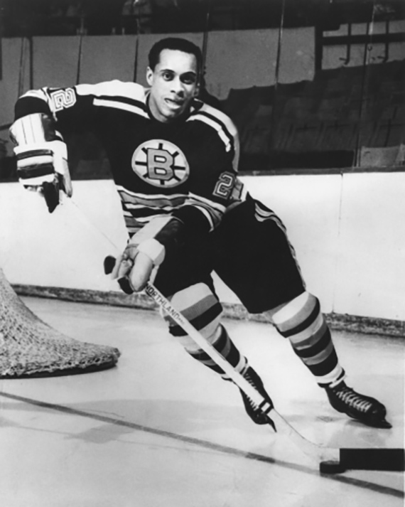A historical photograph of the hockey player Willie O’Ree playing hockey.