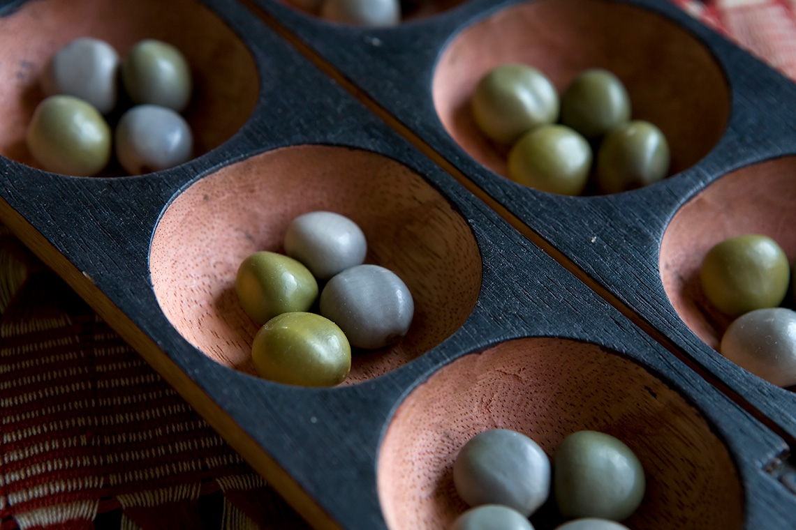 An Oware gameboard, with 12 small round areas scooped out of the wood to hold the pebbles.