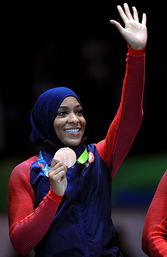 Ibtihaj Muhammad holding her bronze medal, waving