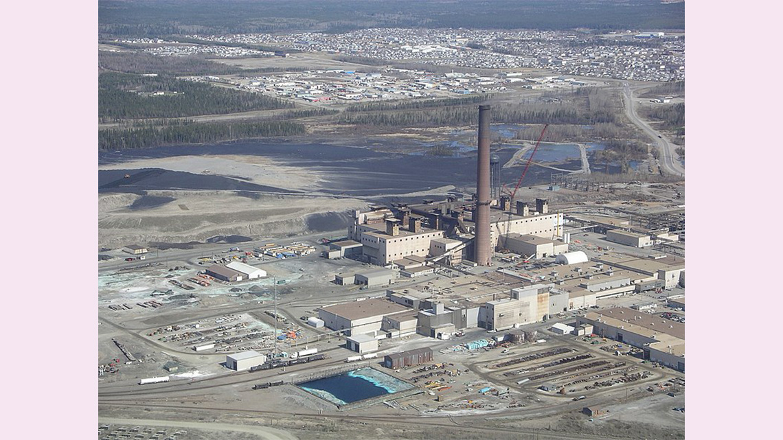 A nickel mine with industrial buildings and a tall chimney, in Ontario.