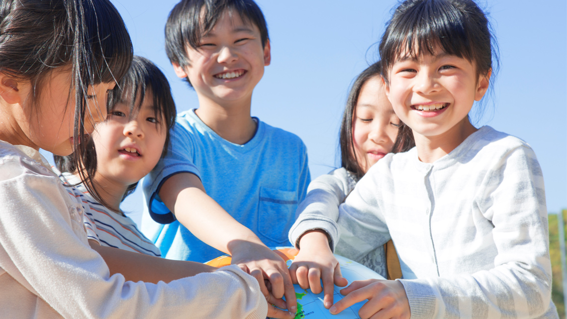 A group of East Asian children holding a globe