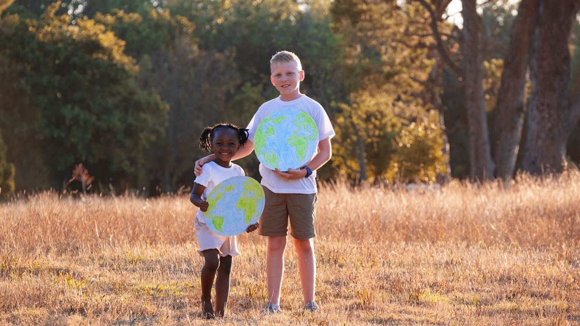 Two African children holding cardboard drawings of Earth