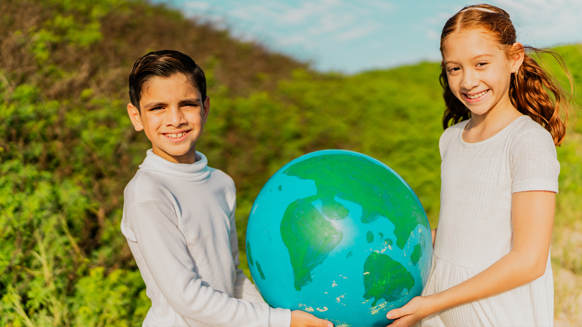Two South American children holding a globe