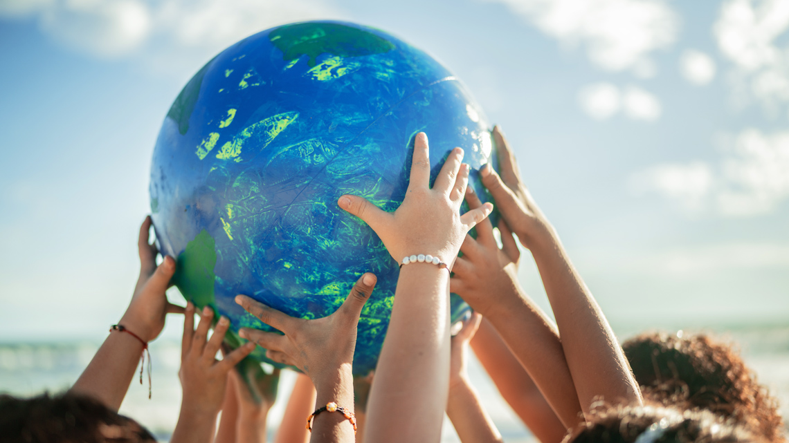 A group of children's hands holding up a model Earth