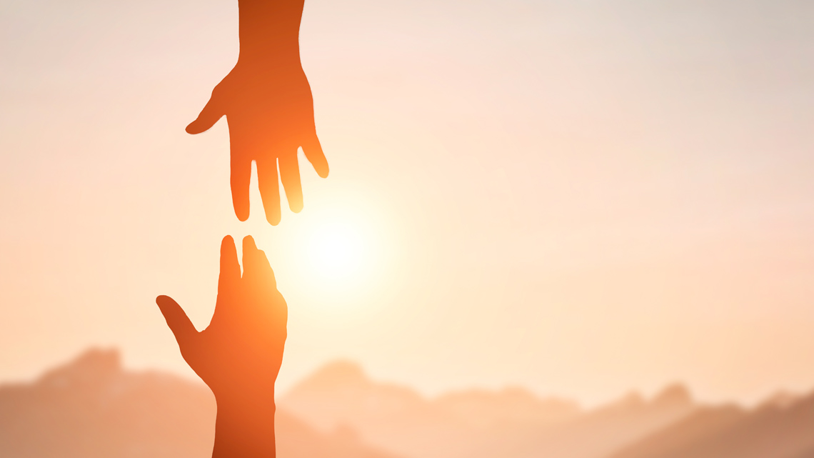 A hand reaching down to grab another person's hand