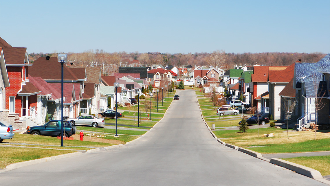 Residential street lines with houses and parked cars.