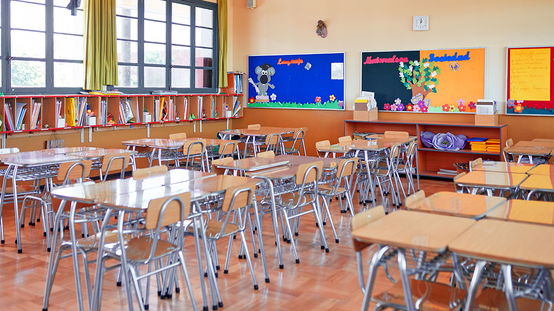 School classroom with neatly arranged chairs and tables and colourful decorations on the wall.