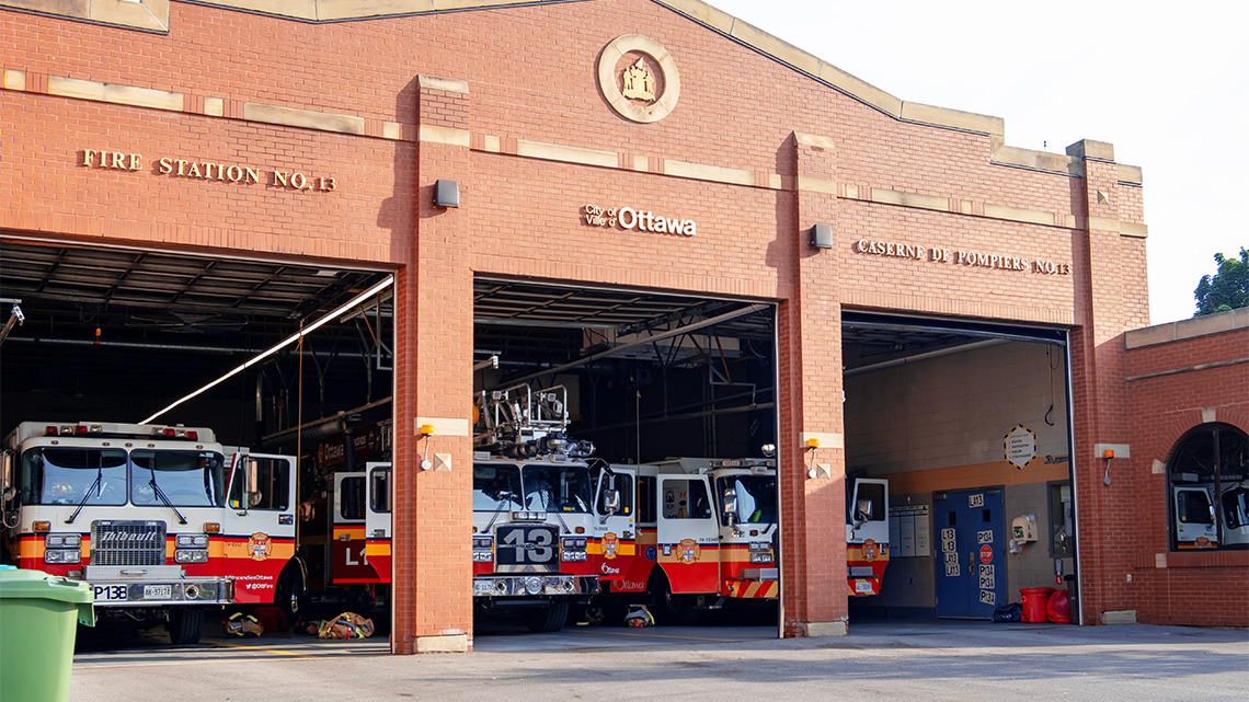 Front view of a fire station with fire trucks parked inside.