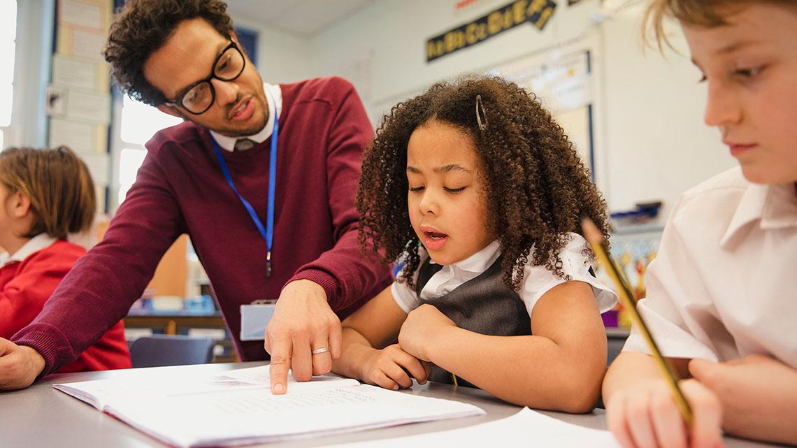 A teacher helping a student at their desk.