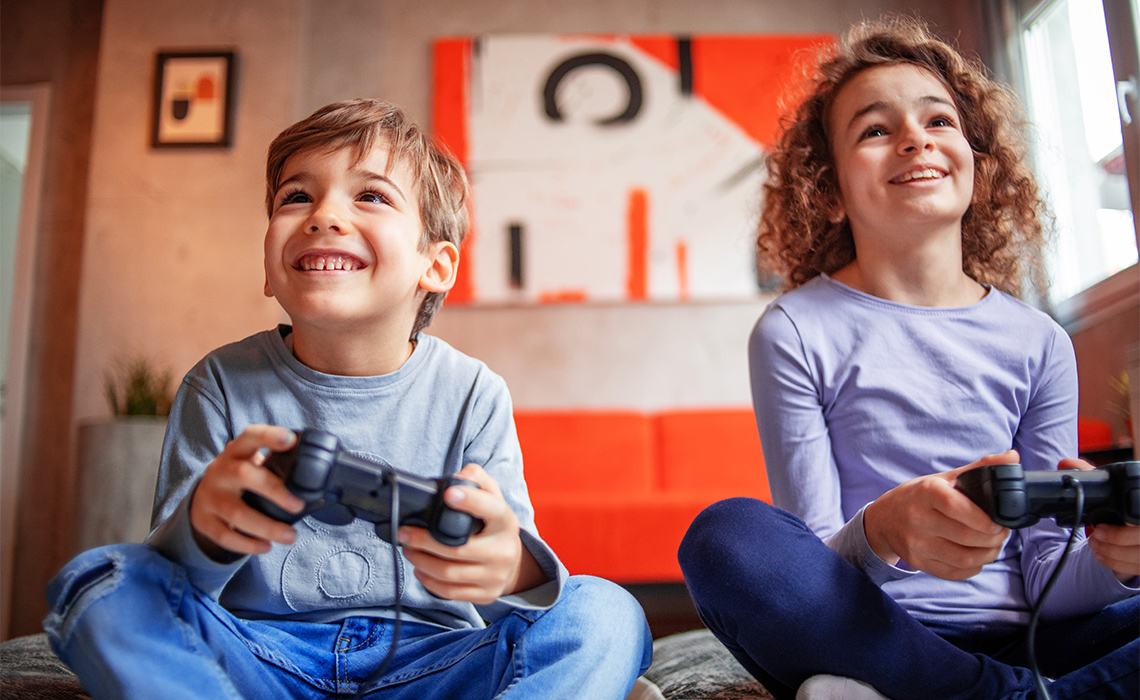 Two smiling children playing a video game.