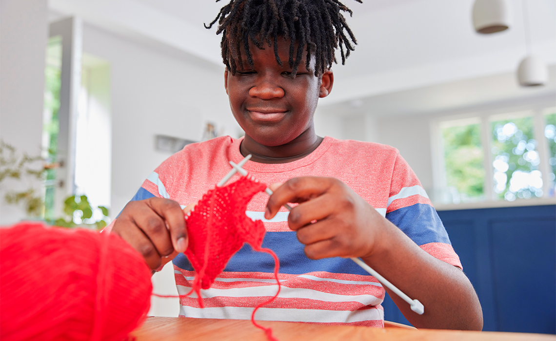 Smiling child knitting.