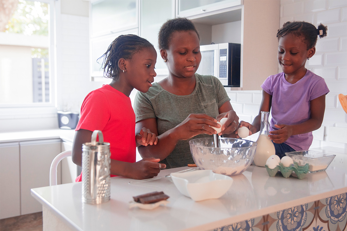 A photo of a mother and two daughters baking.