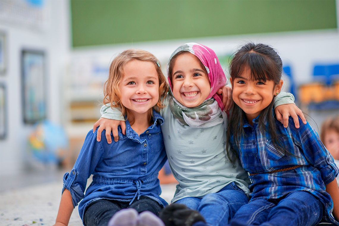 Photo of three young girls smiling at the camera.
