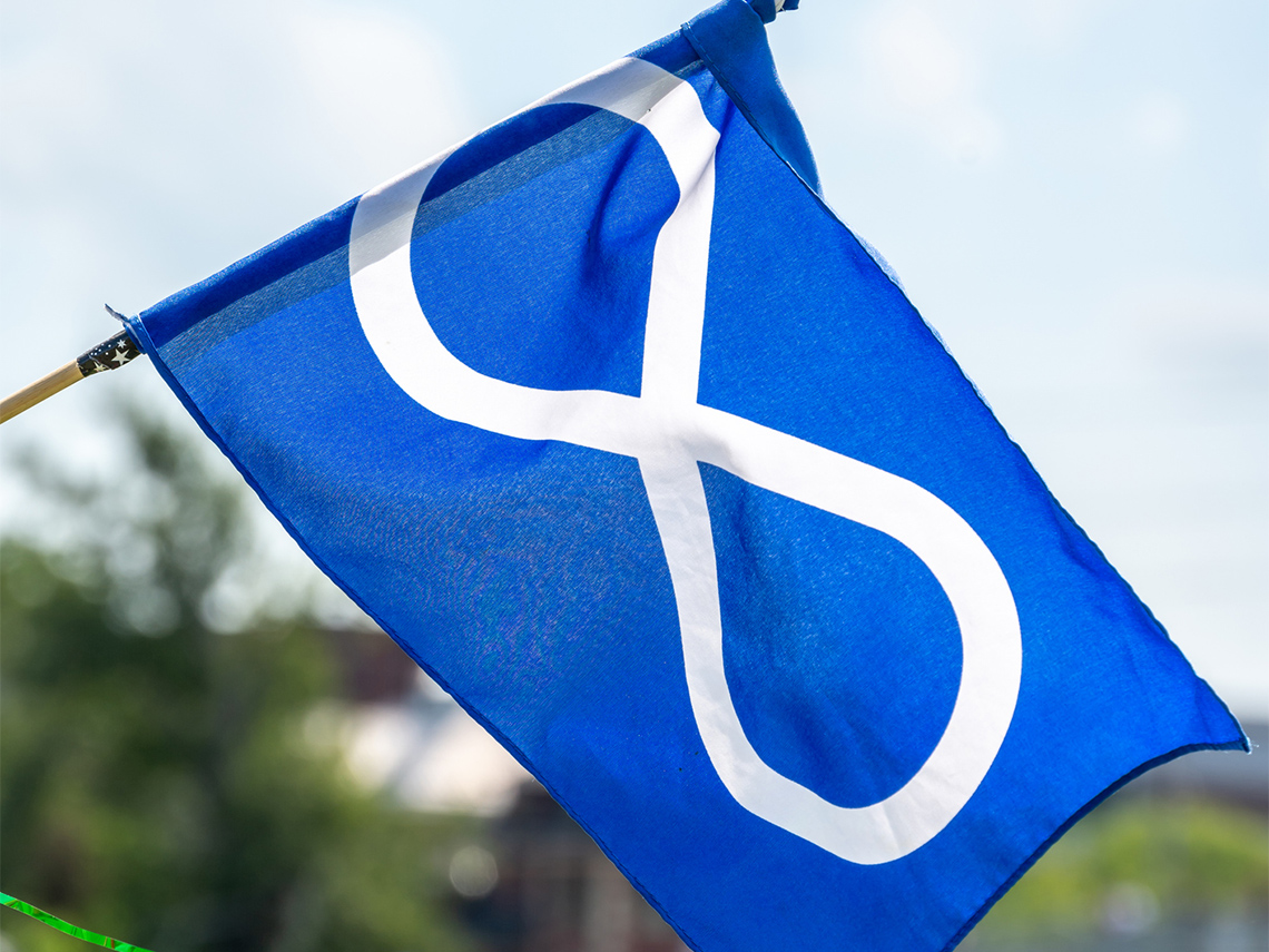 The Métis flag featuring a blue background with a white infinity symbol centered in the middle.