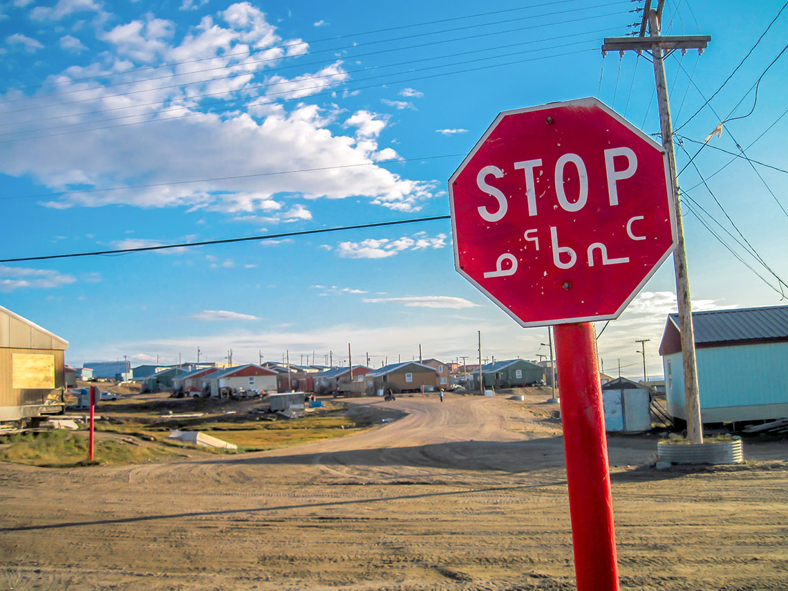 A stop sign with the word stop written in English and written in Inuktitut.