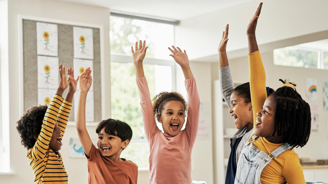 Kids in a classroom standing and stretching their arms