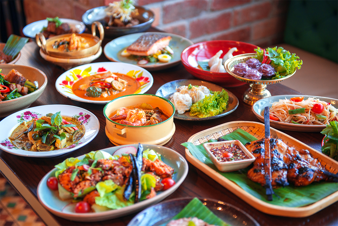 A table with many different Thai foods.