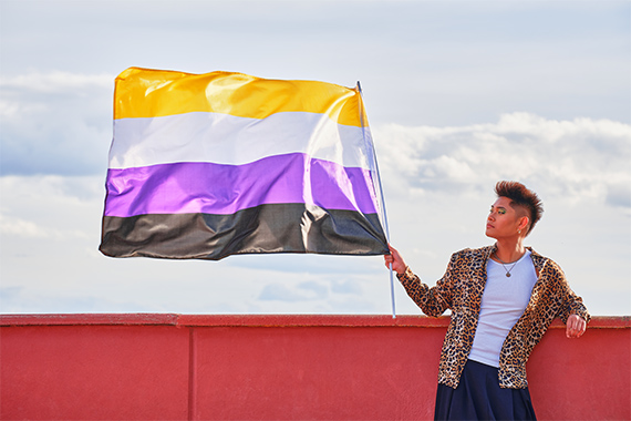 Person waving a flag with black, purple, white, and yellow horizontal stripes