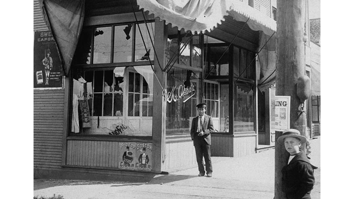 A man standing outside a storefront with damaged windows