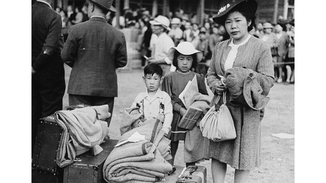 A mother and her two children, with all of their packed-up belongings