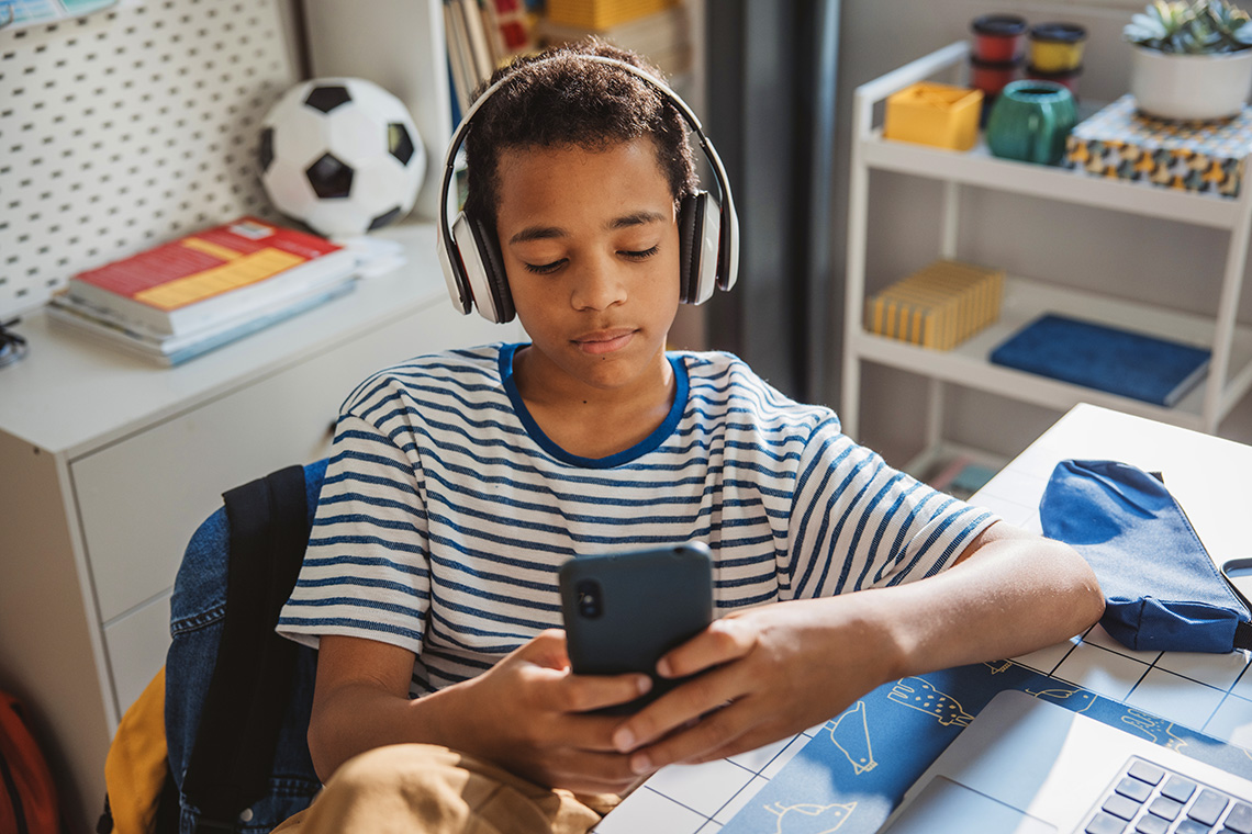 A learner wearing headphones while using a smartphone