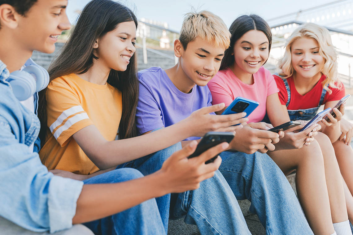 A group of learners showing each other what's on their smartphones and smiling