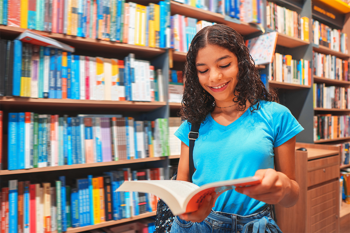 A learner reading a book in a library