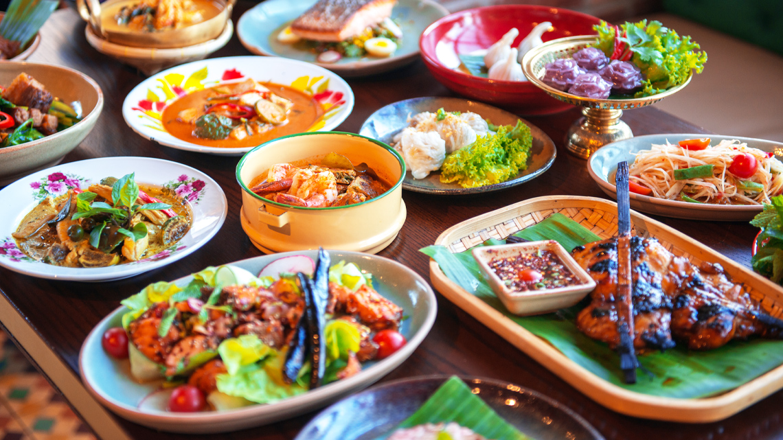 A table with many different Thai foods.