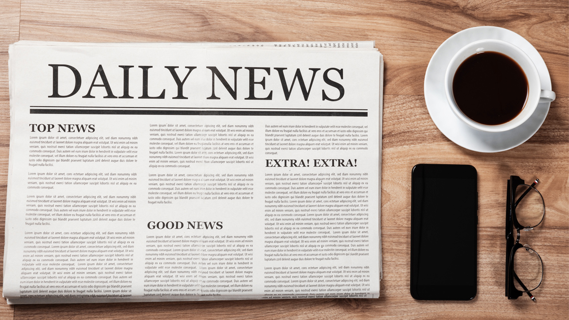 A newspaper called "Daily News" on a table next to a cup of coffee, a pair of glasses, and a smartphone.
