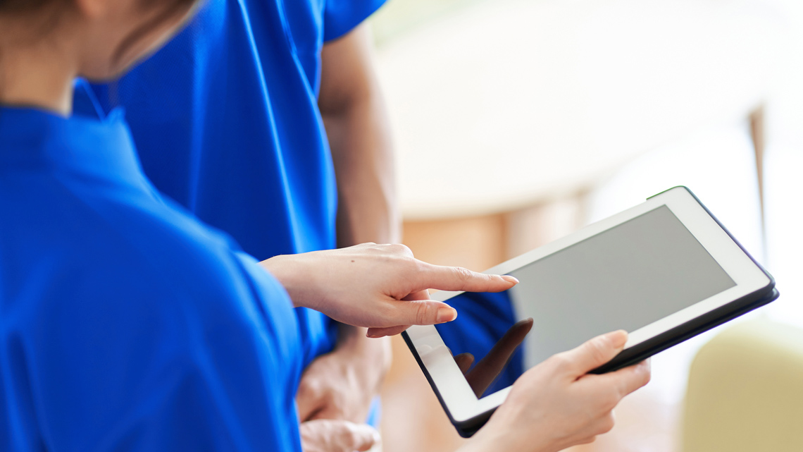 A person holding a tablet and pointing to the screen
