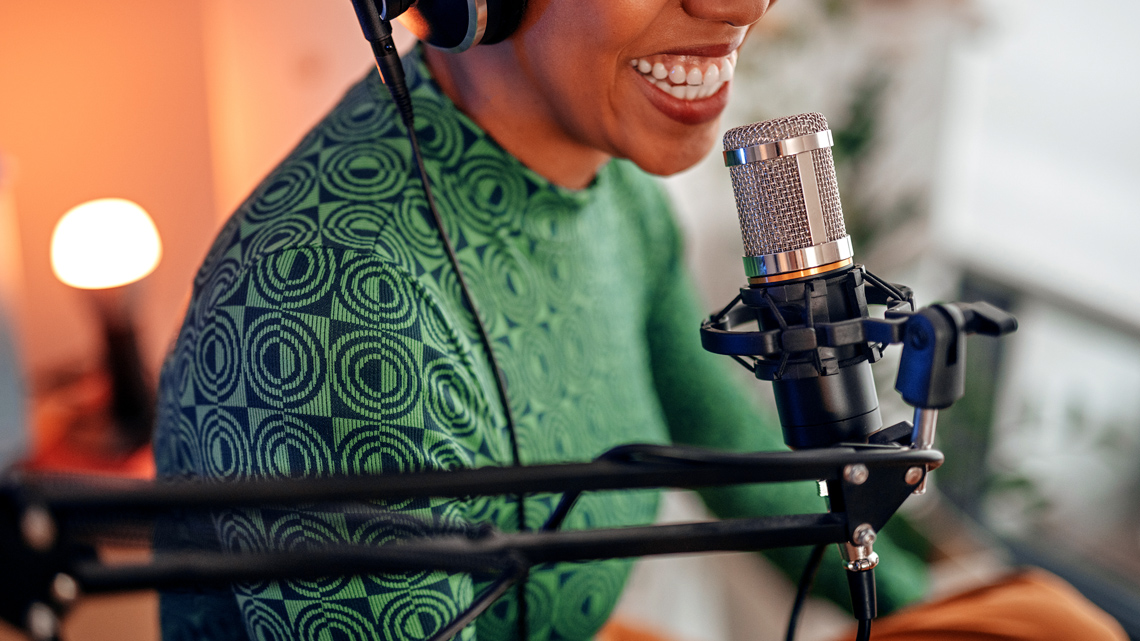 A radio host in a studio speaking into a microphone and wearing headphones