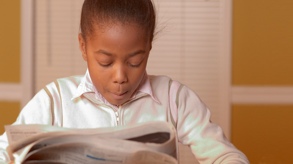 A girl reading the newspaper.