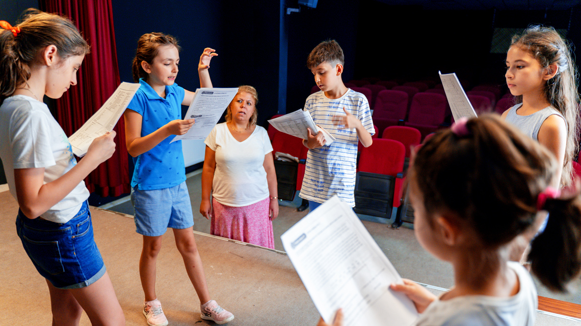 A group of kids on a stage practicing a play performance.