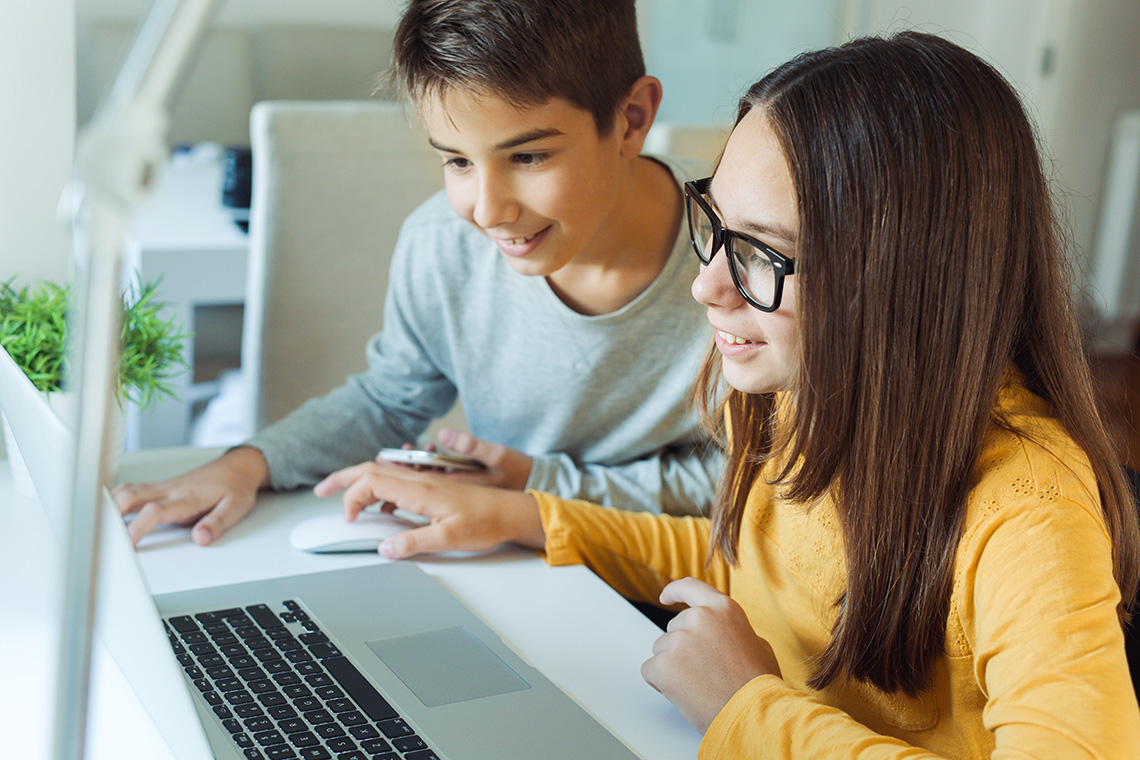 Two young learners looking at a laptop.