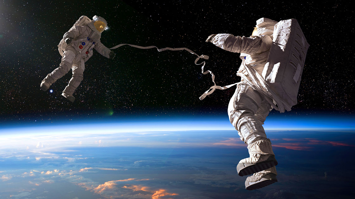 Two astronauts floating in space. The earth is below them.