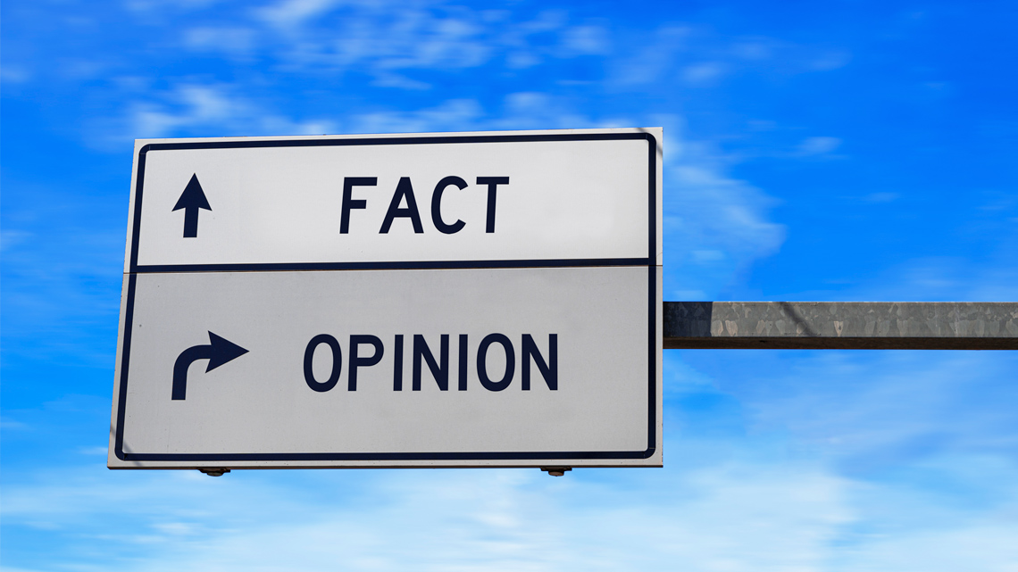 A traffic sign pointing straight for "fact" and right for "opinion."