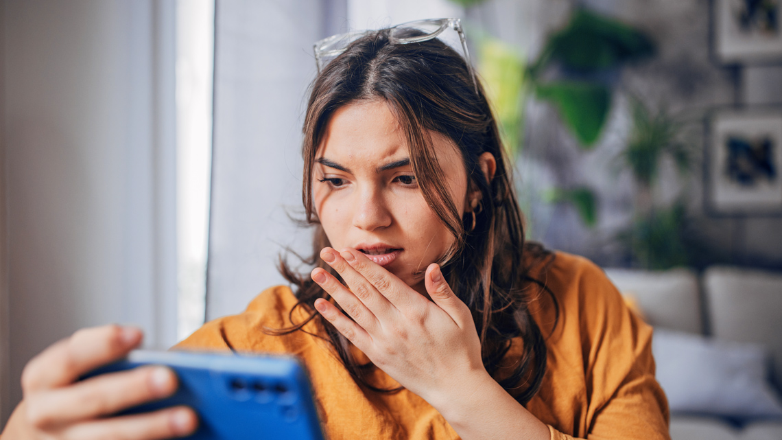 A women looking concerned while looking at her phone.