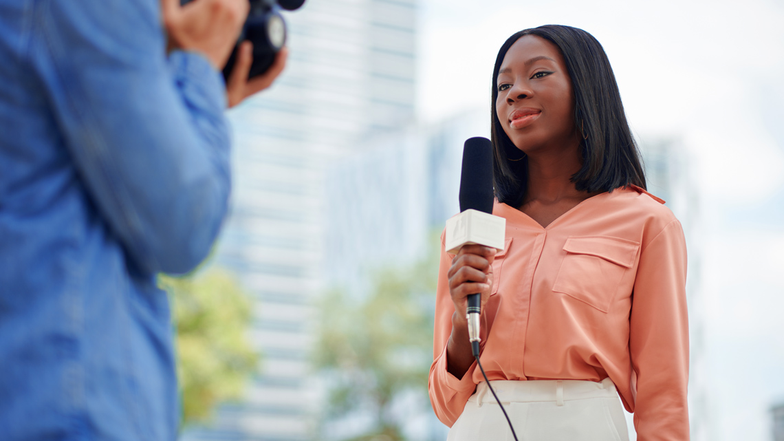 A news reporter speaking into a microphone.