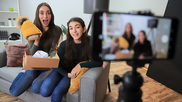 Two teenagers recording a video of them opening gifts.