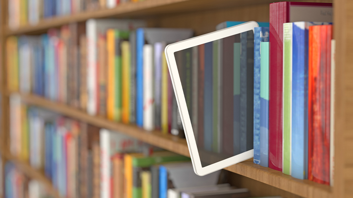 A tablet sticking out on a bookshelf.