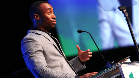 Prince Ea speaking into a microphone at a podium.