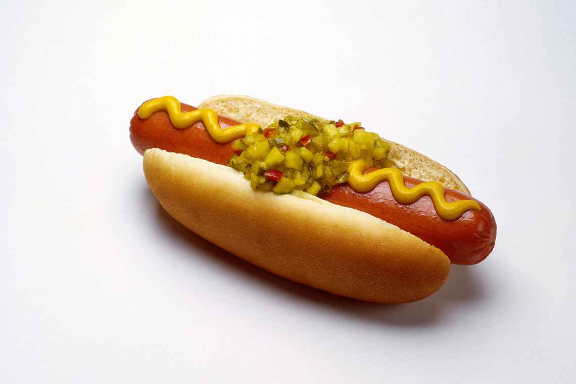 A hot dog in a bun with mustard and relish.